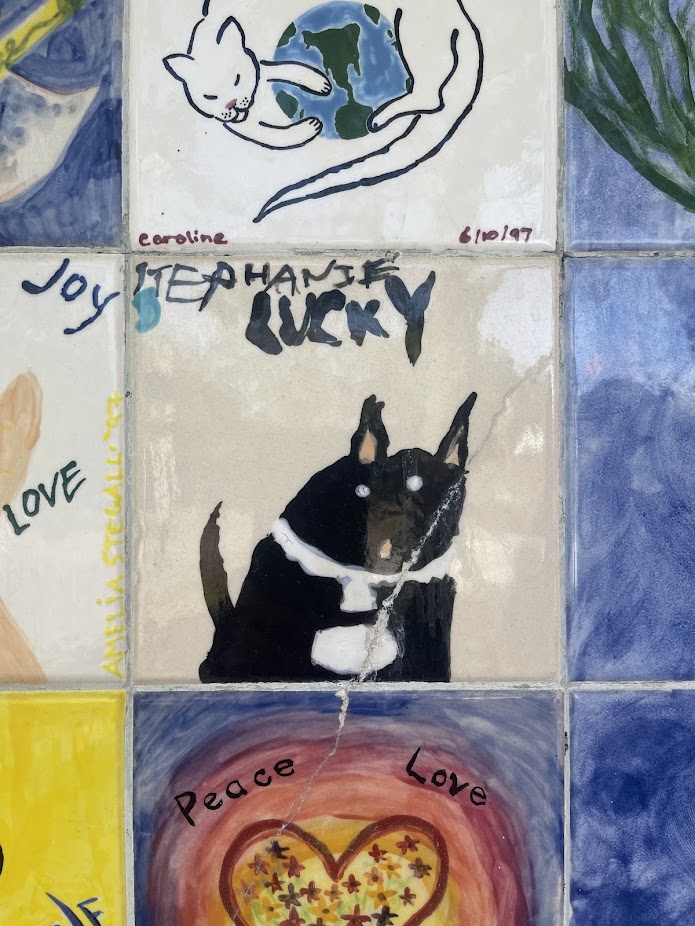a ceramic tile with a black cat painted on